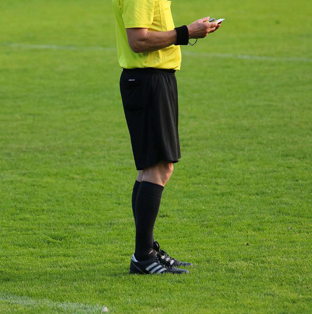 a referee cross-checking a piece of information | soccerfansarena.com